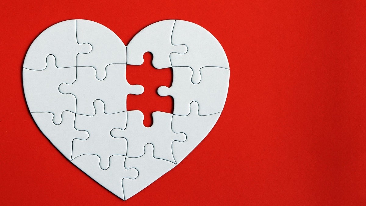 white heart-shaped puzzle on red background with one piece missing