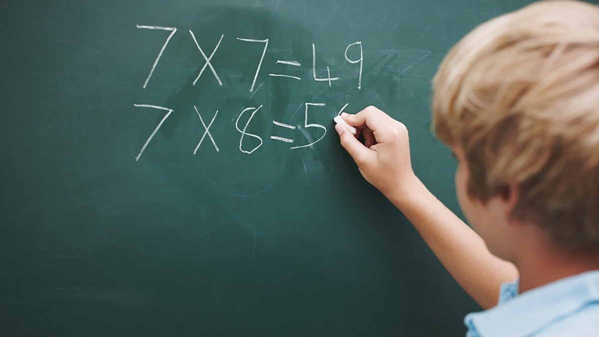 Boy doing multiplication on a blackboard