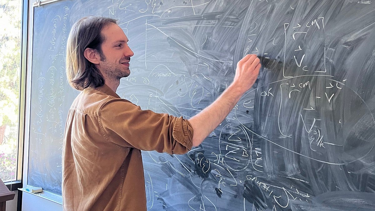 Jesse Hall at a blackboard working on a math equation