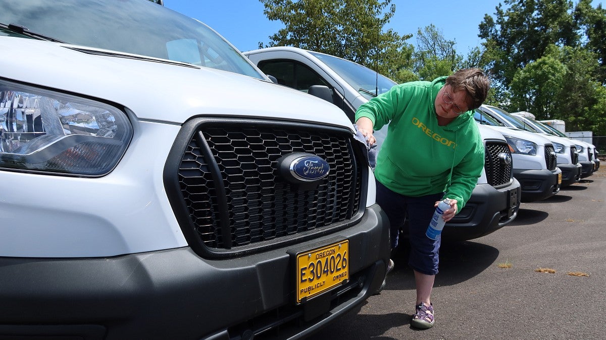 Office specialist Lysha McDowell applies the shine to one of the UO Motor Pool’s 2025 Ford 12-passenger Transit vans