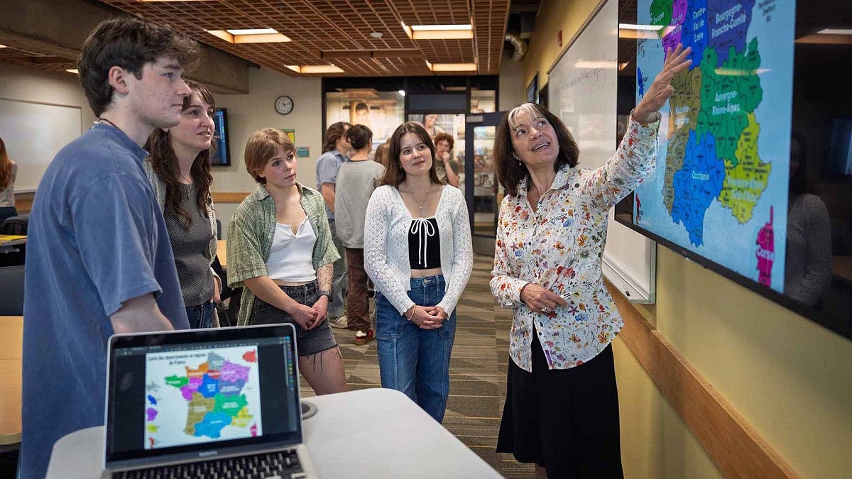 A teacher looking at wall map with students