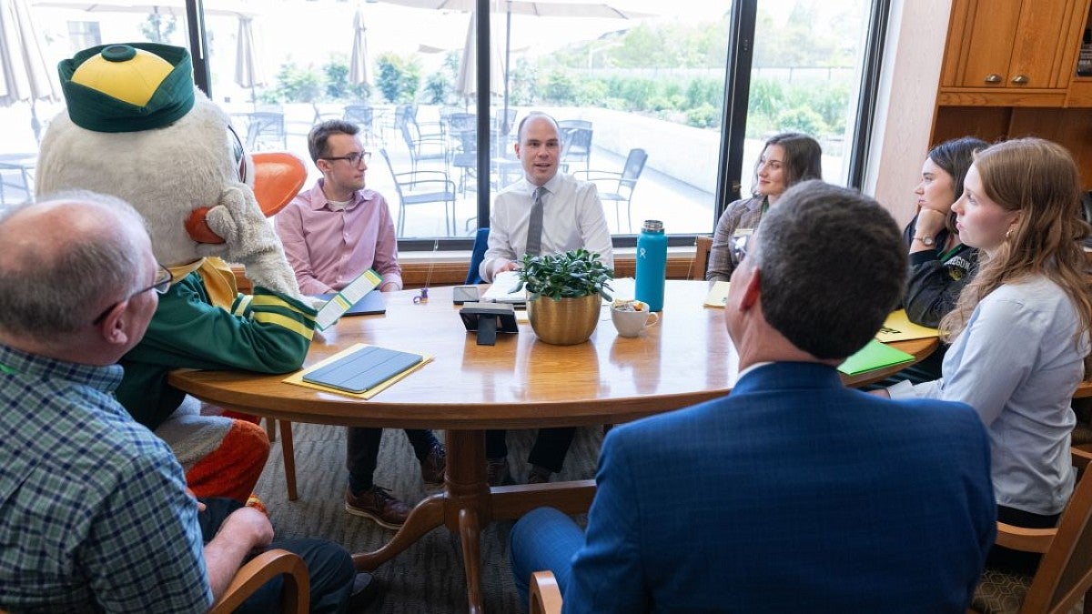 UO employees and the Duck sitting at a round table meeting with a legislator.