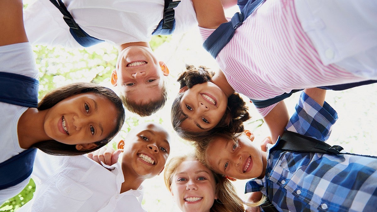 A group of young people gather in a circle looking down at the camera
