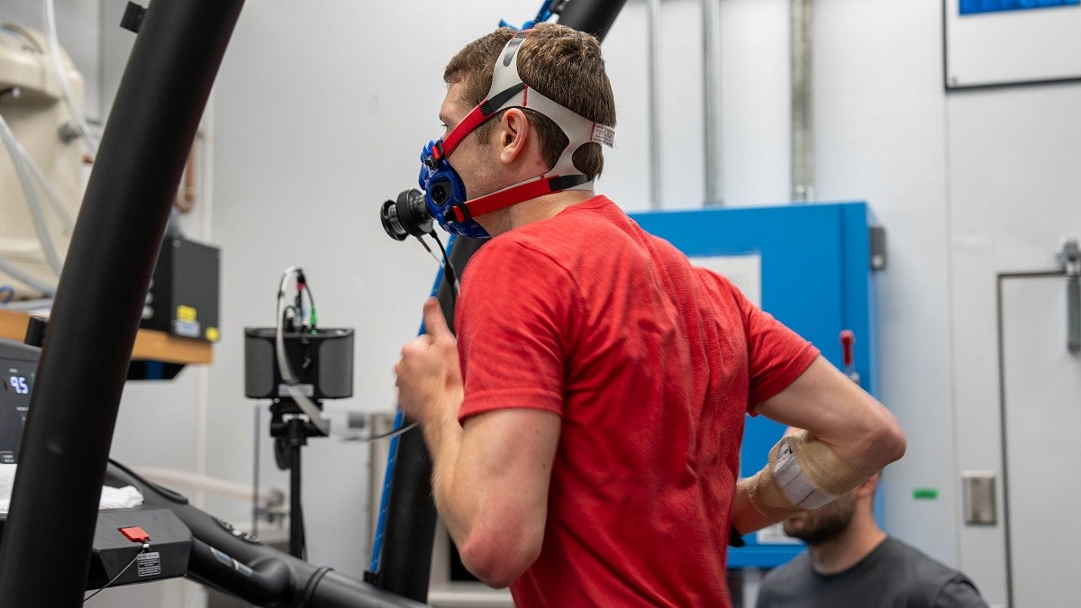 Man with connected to monitoring equipment running on a treadmill