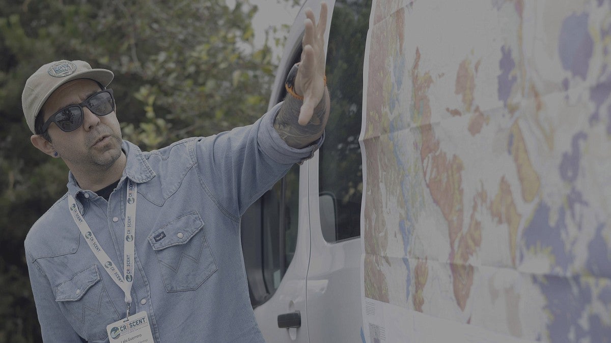 Man explaining a map taped to a van outdoors