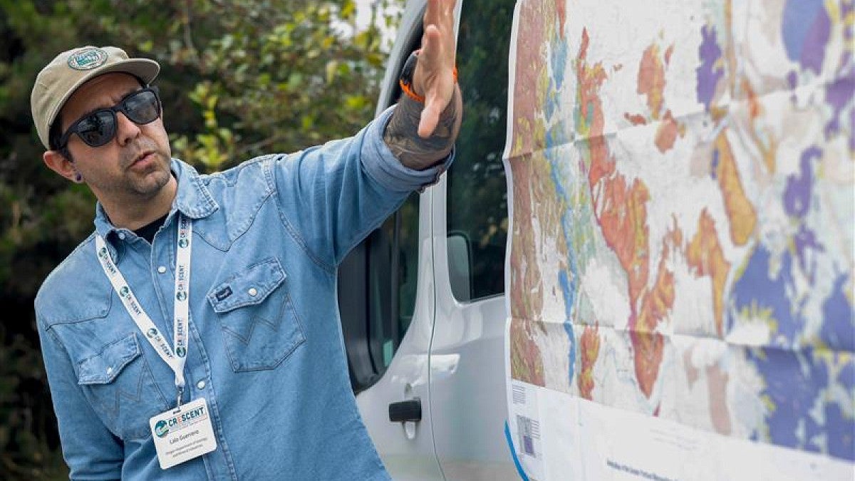 Man gesturing at map taped to a van outdoors