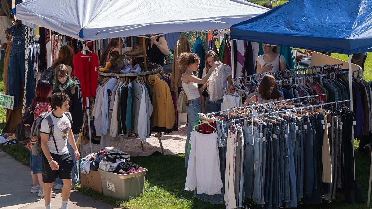 People looking through clothes on racks under canopies