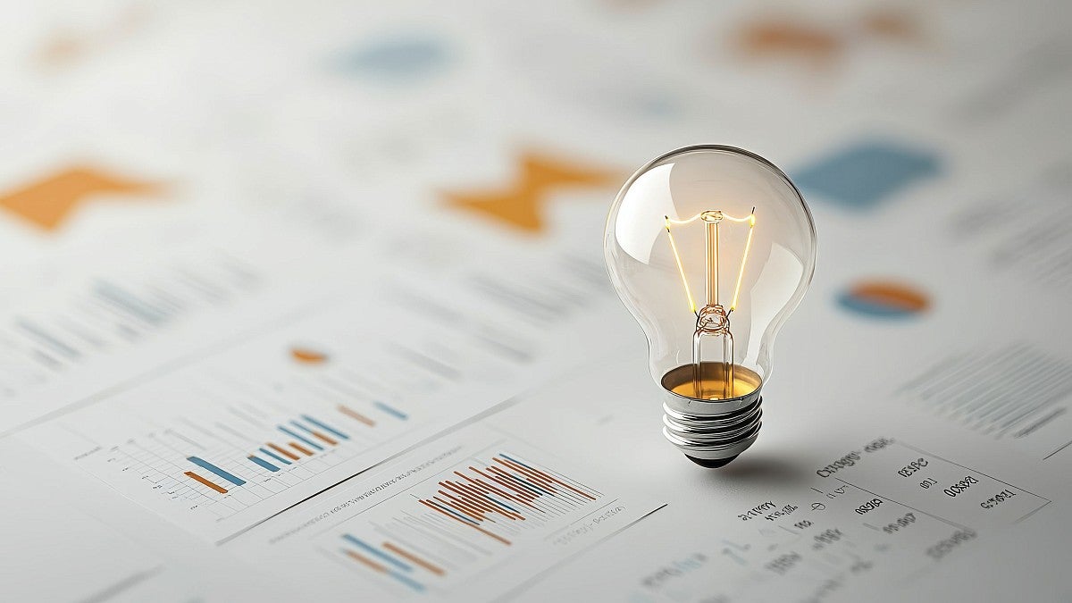 A lit light bulb shining on financial paperwork