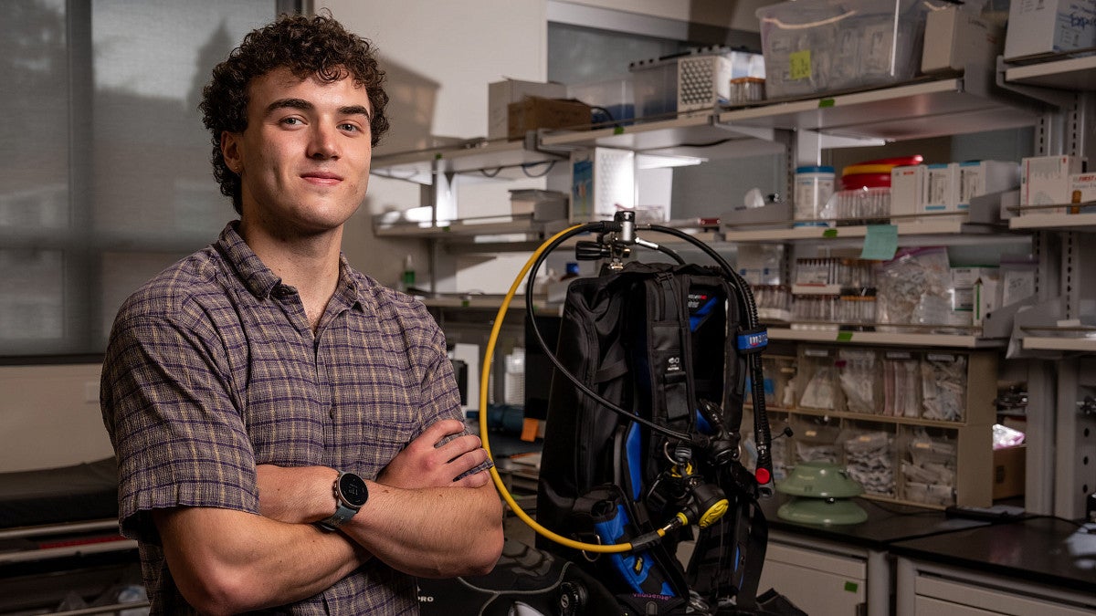 Student posing next to scuba gear
