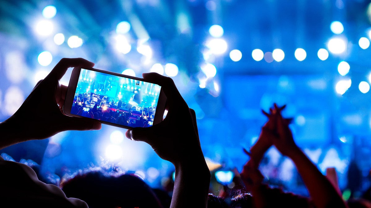 Person holding up a phone camera at a concert