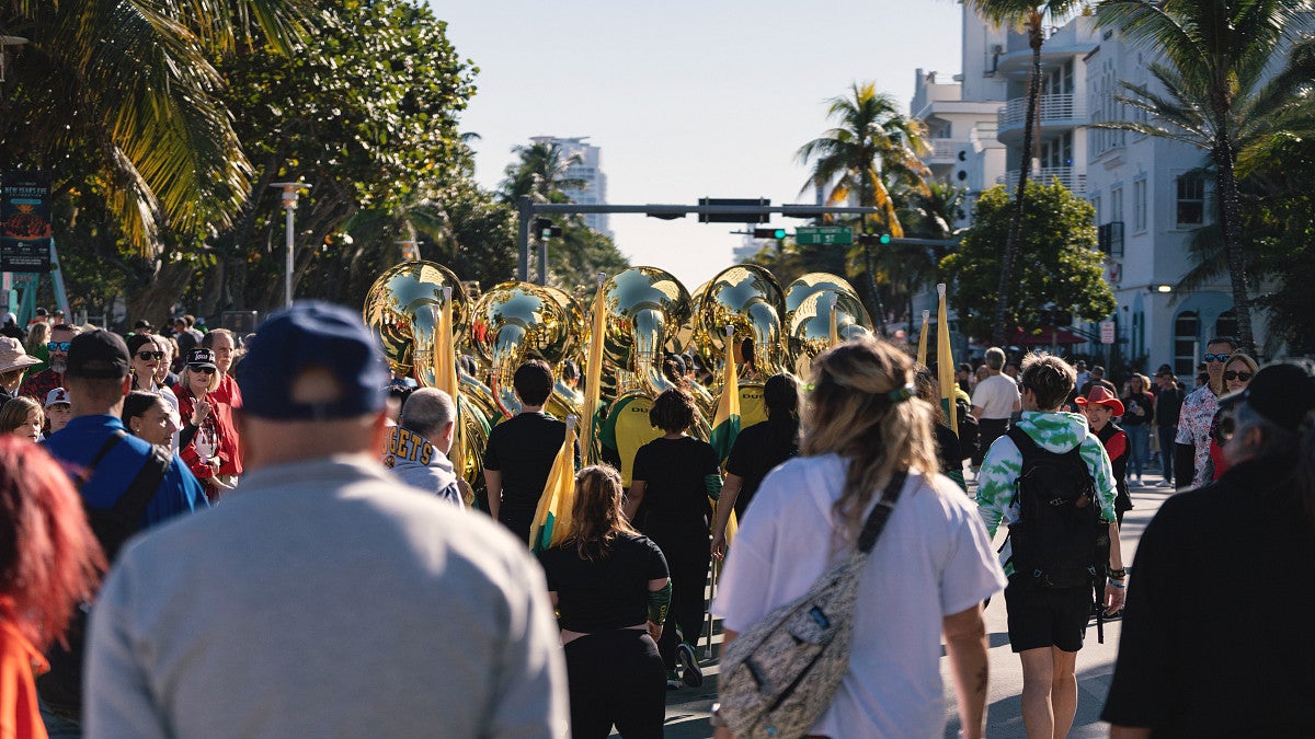 People waking behind the UO marching band at a pep rally