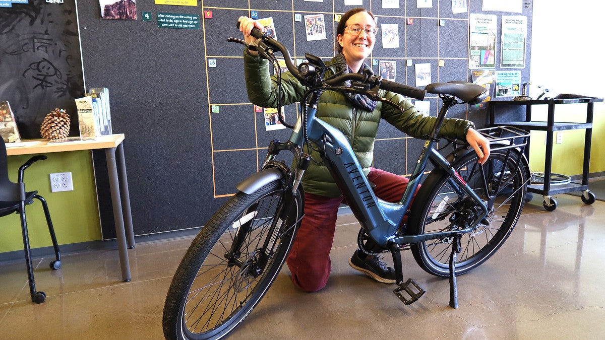 A transportation solutions expert kneels next to an electric bike