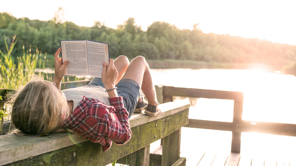 Girl reading by a lake