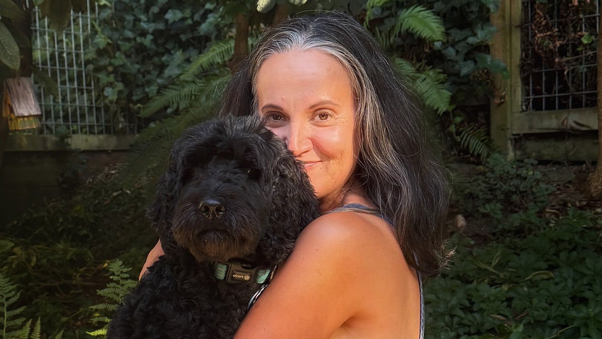Sousa-Ransford, holding her black Labradoodle Lyra, has come to enjoy canine companionship