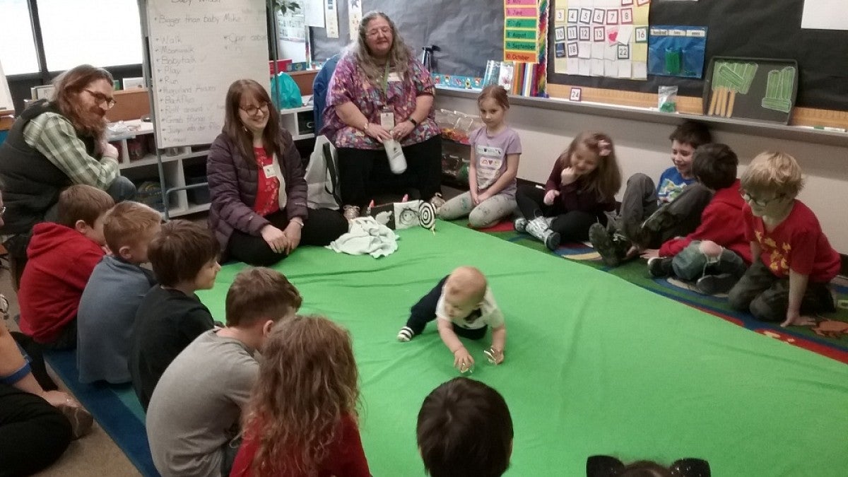 Children and adults watching a baby