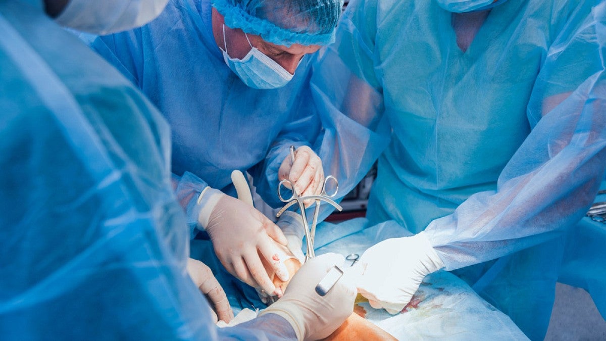 Trauma surgeons work on the leg of an injured patient