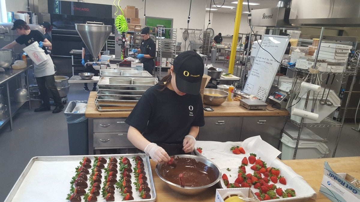 Chefs dipping strawberries in chocolate in the new central kitchen.