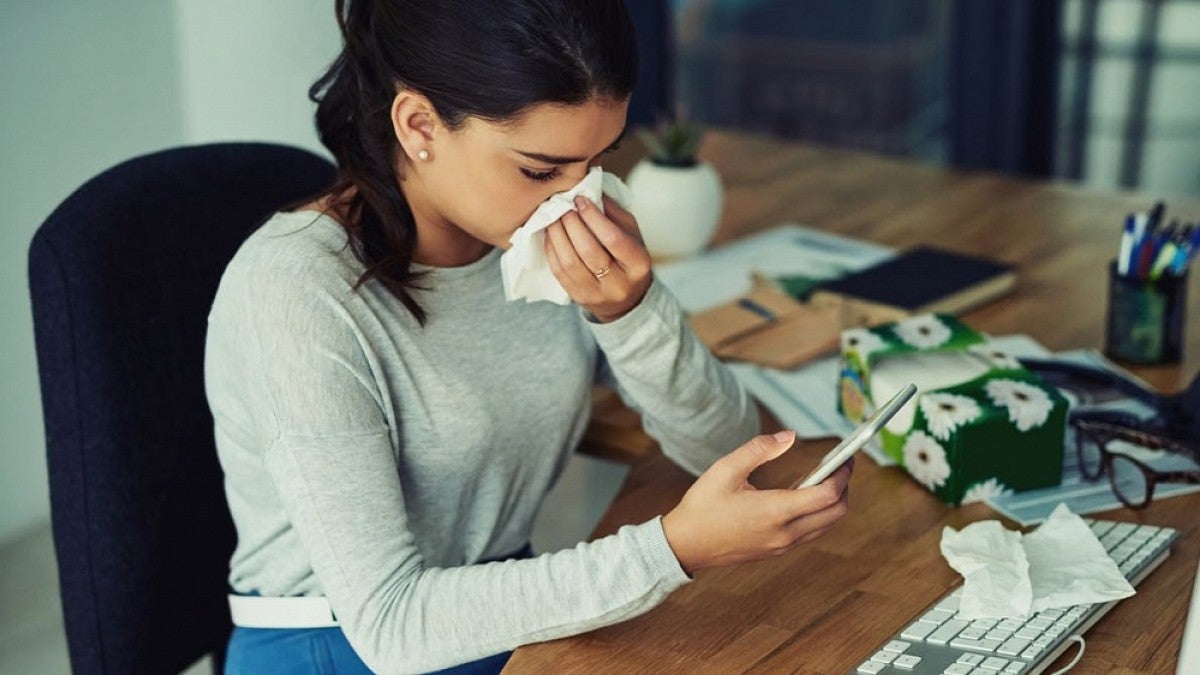 Worker using tissue at her desk