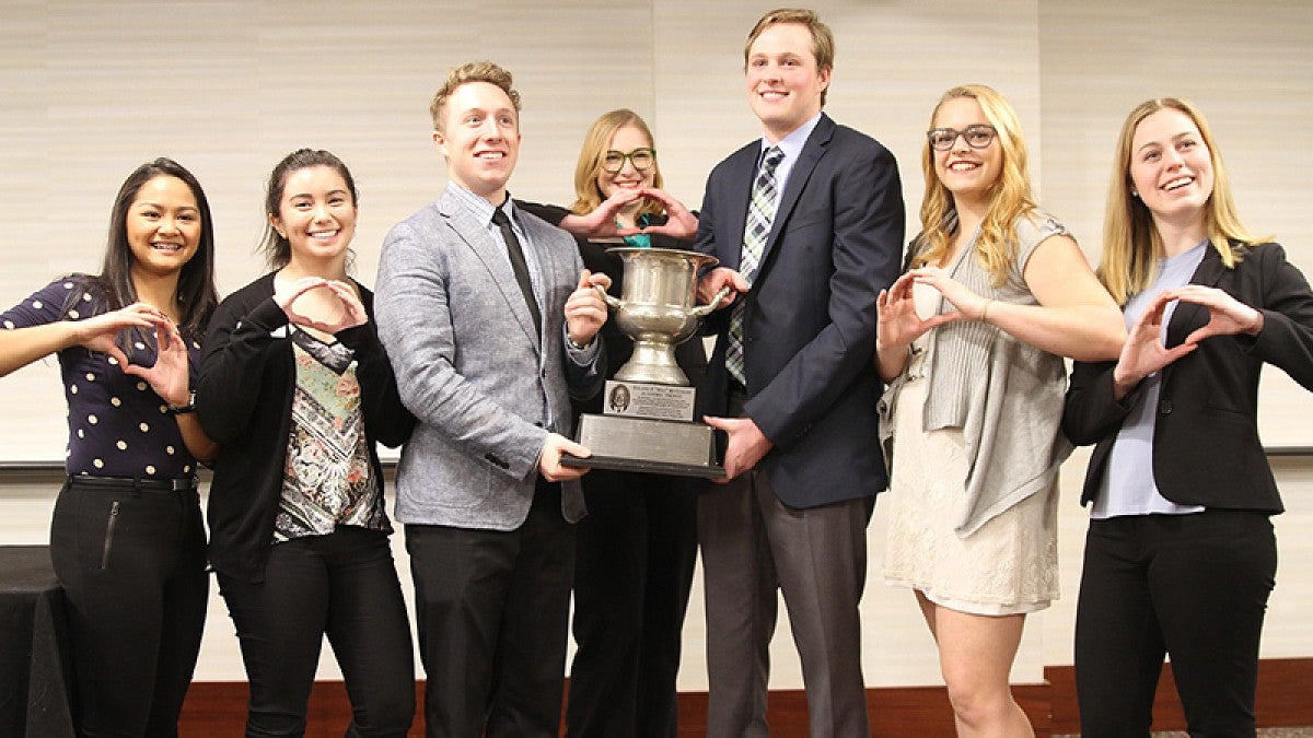 Evans Scholars holding trophy