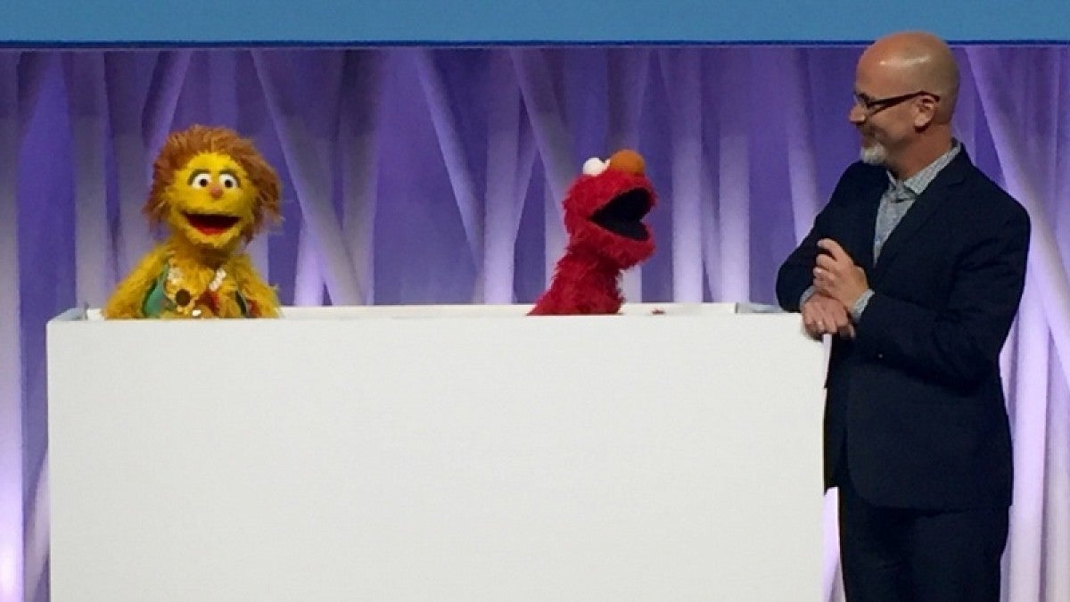 Phil Fisher interacting with a muppet during a conference presentation
