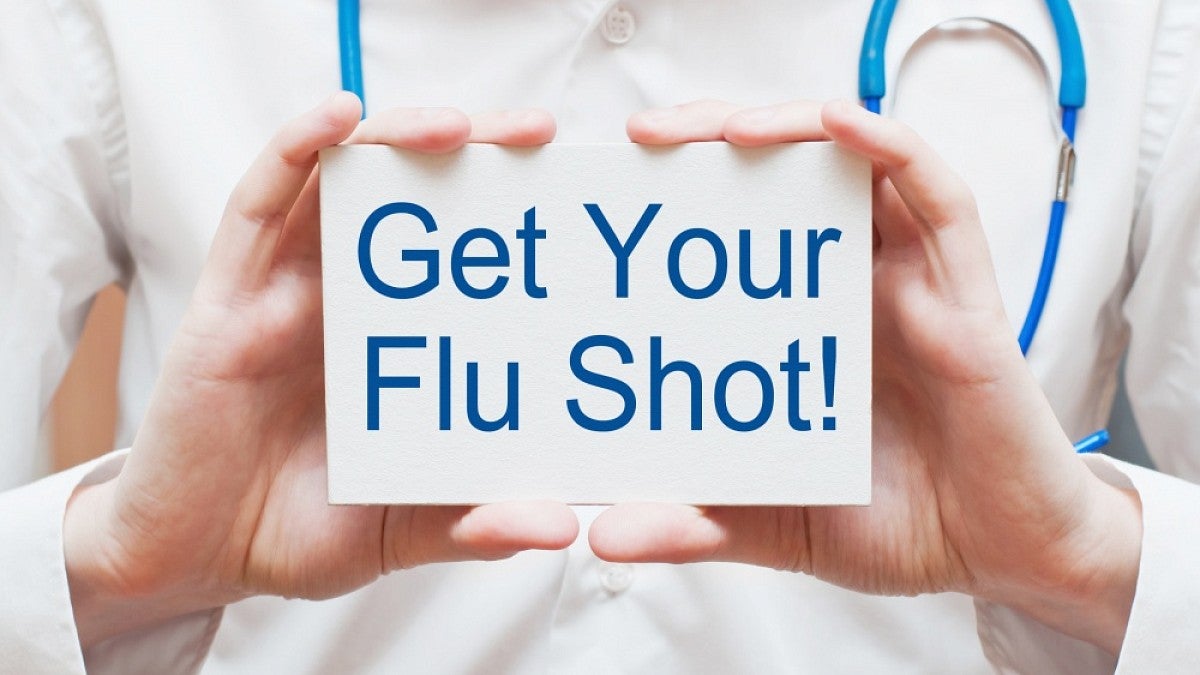 Doctor holding card reading 'Get your flu shot'