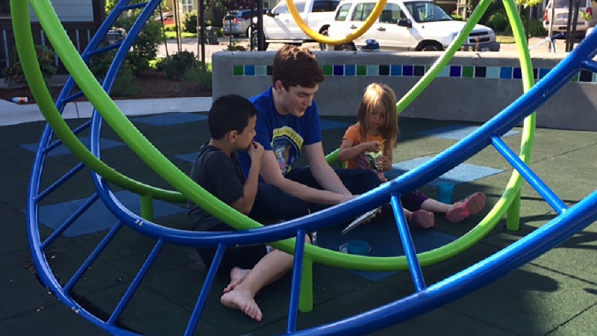 UO student reading to children at a playground