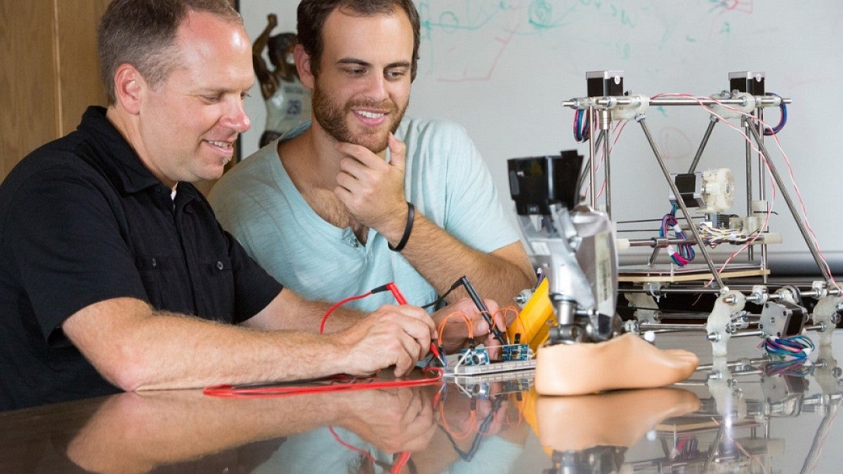 Two men working on a prosthetic foot.