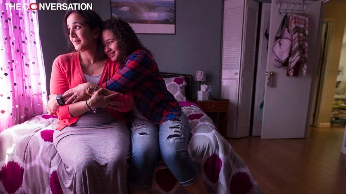 Mother and daughter sitting on bed