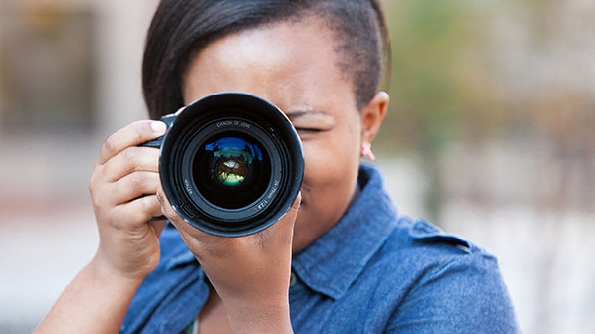 Polly Irungu looking through a camera lens