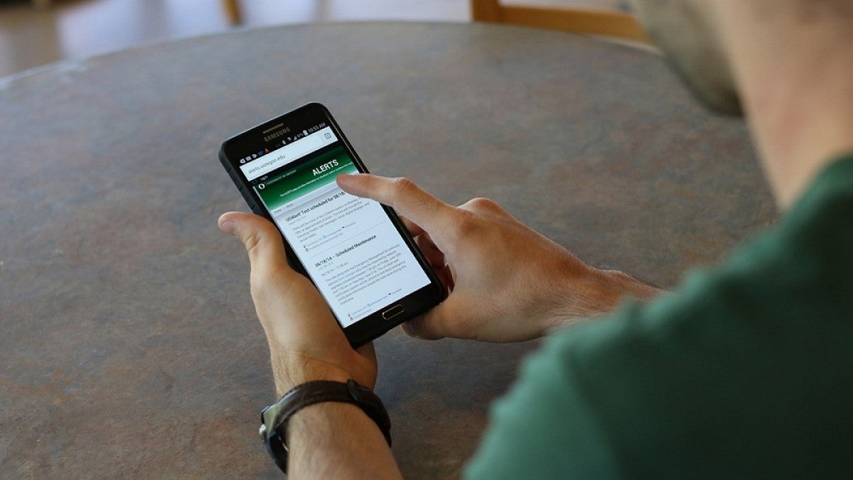 Man looking at UO Alert on smartphone