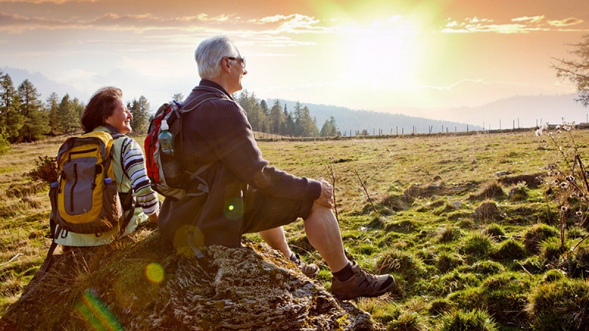 Stock image of two people sitting on a rock while on a hike.