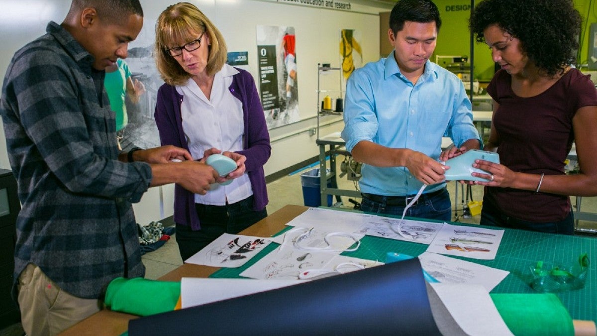 SPM Director Ellen Schmidt-Devlin (second from left) demonstrates footwear-making tools