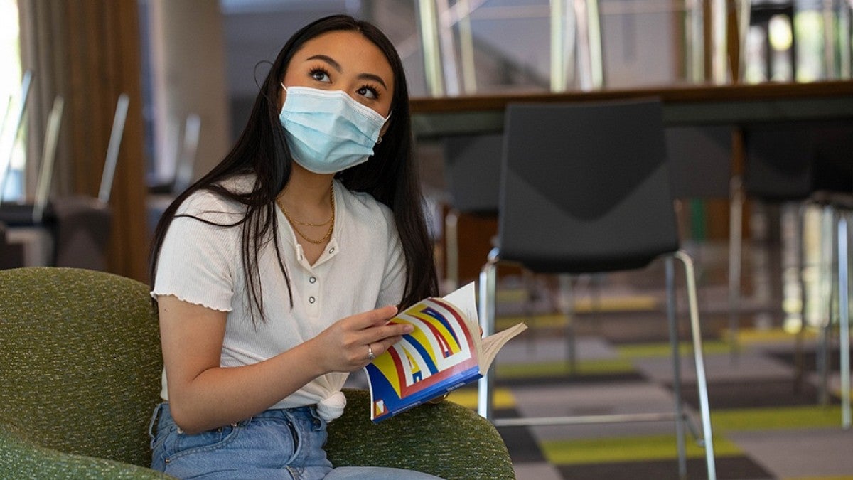 Masked student reading book