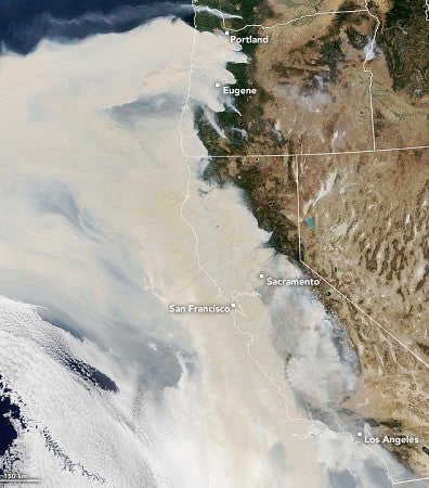 A satellite image shows widespread coverage of thick smoke over Oregon, California, and the Pacific Ocean but clear air elsewhere. Cities marked as impacted are Portland, Eugene, Sacramento, San Francisco, and Los Angeles.