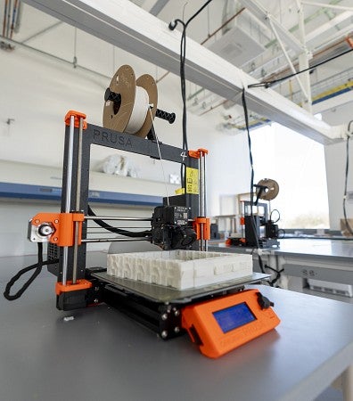 Orange 3D printer sitting on lab bench