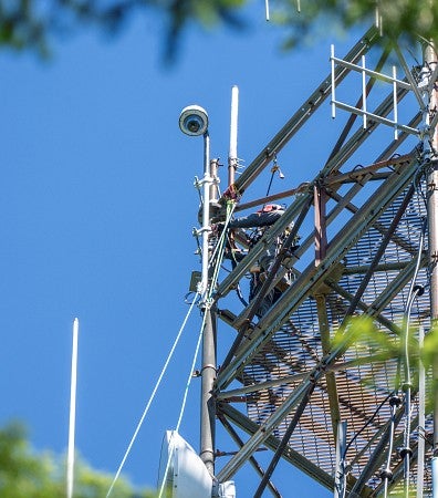 A man fastens a camera at the top of the tower