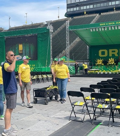 Volunteers place water bottles and towels on chairs for a commencement ceremony
