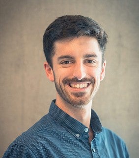 Paul Kempler wearing a blue shirt with a grey backdrop