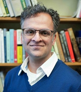 image of Arafaat Valiani standing in front of a bookshelves