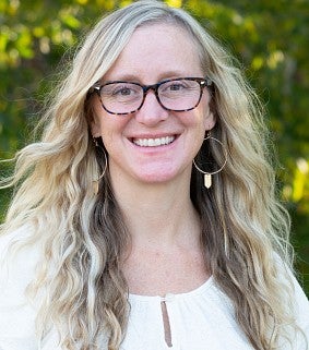 Sara Schmitt smiling outside with trees in the background