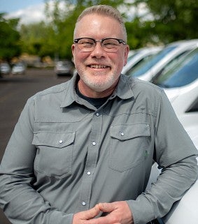 A man smiles while leaning against a new van