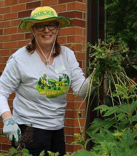 An employee pulls weeds in front of a building