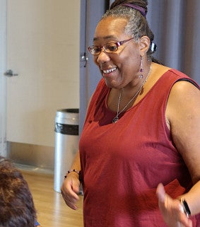 A woman smiles while gesturing to another woman