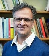 image of Arafaat Valiani standing in front of a bookshelves