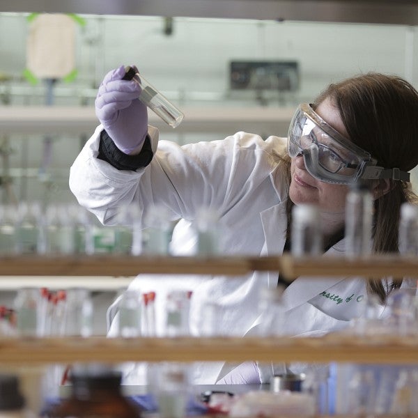 Scientist in lab looks at test tube