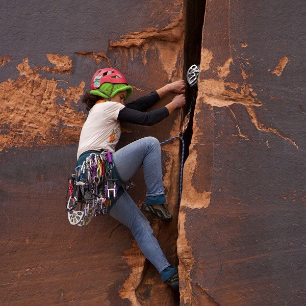 A woman hooked up to ropes, climbing a sheer rock face