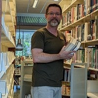 Michael Brown holds books in the UO Portland Library.